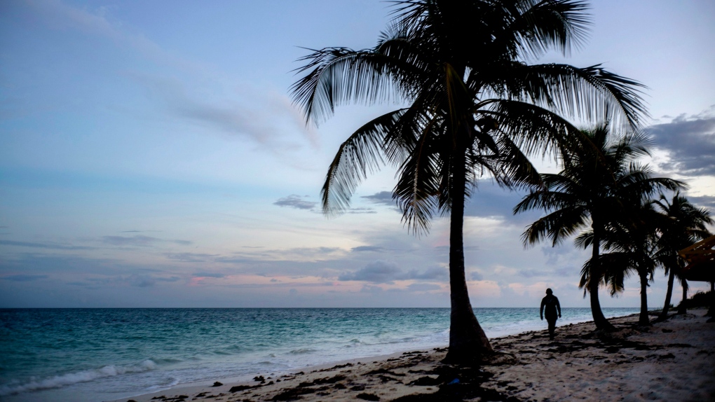 This Aug. 31, 2019 file photo shows a woman walking along a beach before the arrival of Hurricane Dorian in Freeport, Grand Bahama, Bahamas. (AP Photo/Ramon Espinosa, File)