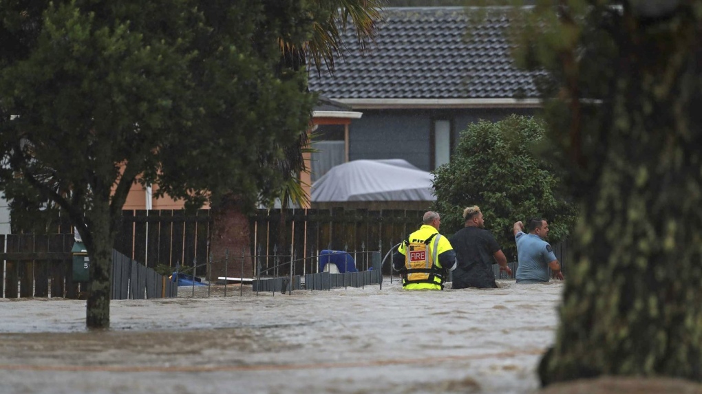 Emergency workers and a man wade through flood waters in Auckland, New Zealand, Friday, Jan. 27, 2023. Torrential rain and wild weather in Auckland causes disruptions throughout the city and an Elton John concert to be canceled just before it was due to start. (Hayden Woodward/New Zealand Herald via AP)