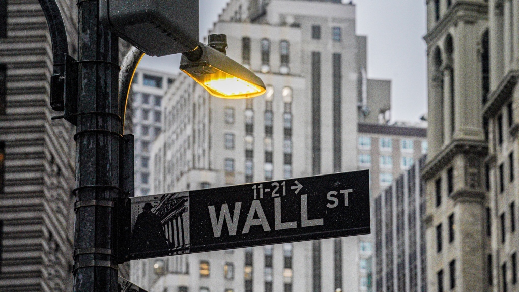 A street light brightens a Wall Street sign outside the New York Stock Exchange, Oct. 3, 2022, in New York. (AP Photo/Bebeto Matthews)