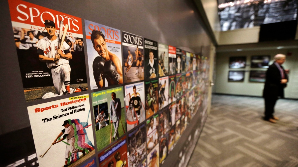 The Sports Museum curator Richard Johnson, right, stands near an exhibit that displays cover photos from the sports magazine Sports Illustrated in the museum at the TD Garden, in Boston on Thursday, Dec. 17, 2015. (AP Photo/Steven Senne)