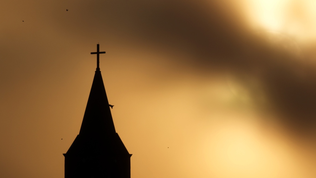 The sun is shrouded in clouds as it sets beyond St John the Baptist Catholic Church in Kansas City, Kan., Thursday, Dec. 22, 2022. (AP Photo / Charlie Riedel / File)