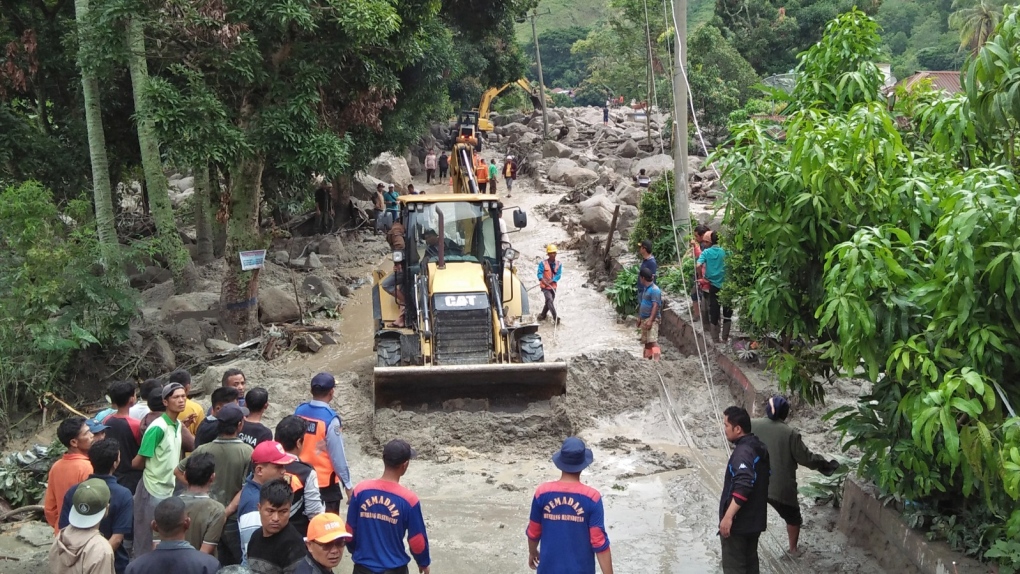 Rescue workers use heavy machines to clear a road from rock and mud following a landslide in Simangulampe village, North Sumatra, Indonesia, Saturday, Dec. 2, 2023. Torrential rain triggered flash floods and a landslide on Indonesia's Sumatra island, leaving a number of people missing, officials said Saturday. (AP Photo/Hermanto Tobing)