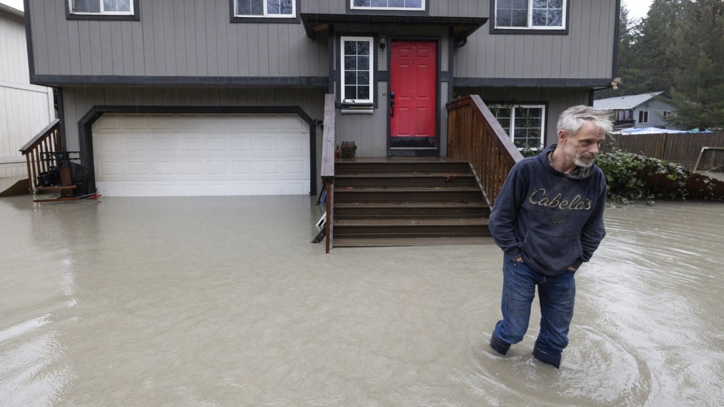 Bernie Crouse wades through water outside his home after the nearby South Fork Stillaguamish River crested early in the morning flooding several houses in this neighbourhood, Dec. 5, 2023, in the Arlington area of Seattle, Washington. Crouse got his dog Max out of the basement as it began flooding, after getting a call from another neighbour. (Ken Lambert/The Seattle Times via AP)