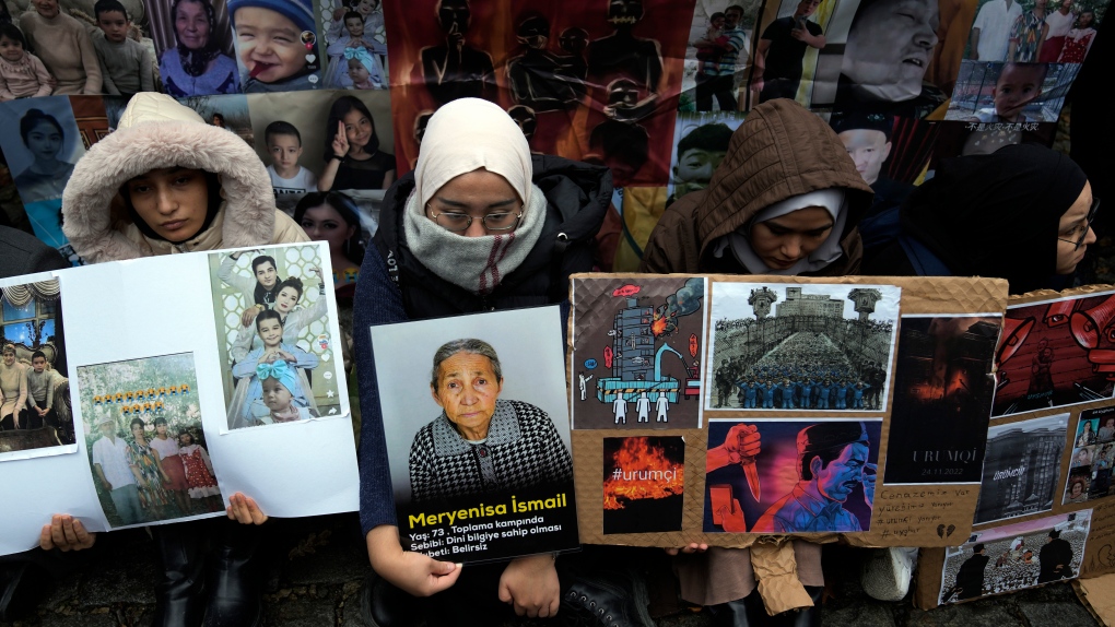 Women sit holding pictures of victims in front of the Chinese consulate in Istanbul, Nov. 30, 2022. MPs will vote on whether to start a refugee program to resettle 10,000 Uyghurs fleeing persecution in China. (THE CANADIAN PRESS- AP-Khalil Hamra)