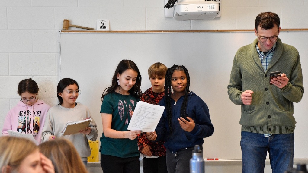 Teacher Donnie Piercey, right, works with students as they perform a three-scene play written by ChatGPT during his class at Stonewall Elementary in Lexington, Ky., Monday, Feb. 6, 2023. Parameters of the play were entered into the ChatGPT site, along with instructions to set the scenes inside of a fifth-grade classroom. Line-by-line, it generated fully-formed scripts, which the students edited, briefly rehearsed and then performed. (AP Photo/Timothy D. Easley)