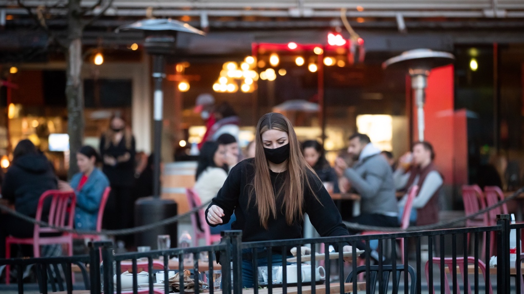 A server clears a table on a patio at a restaurant, in Vancouver, on Friday, April 2, 2021. THE CANADIAN PRESS/Darryl Dyck