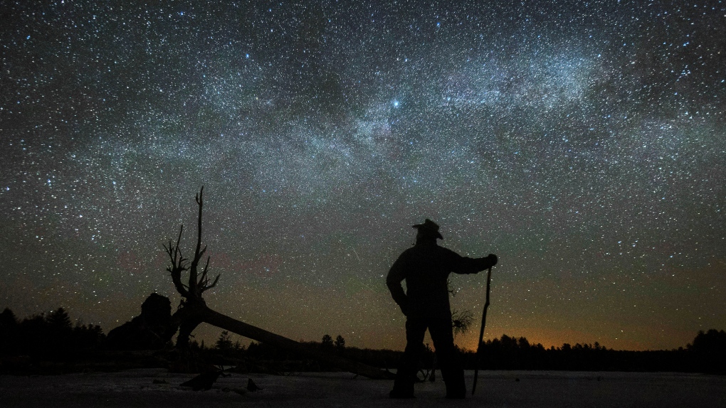 Stargazer Dave Cooke observes an unusual placement of the Milky Way, over a frozen fish sanctuary in central Ontario, north of Hwy 36 in Kawartha Lakes, Ont., on Sunday, March 21, 2021. (THE CANADIAN PRESS/Fred Thornhill)