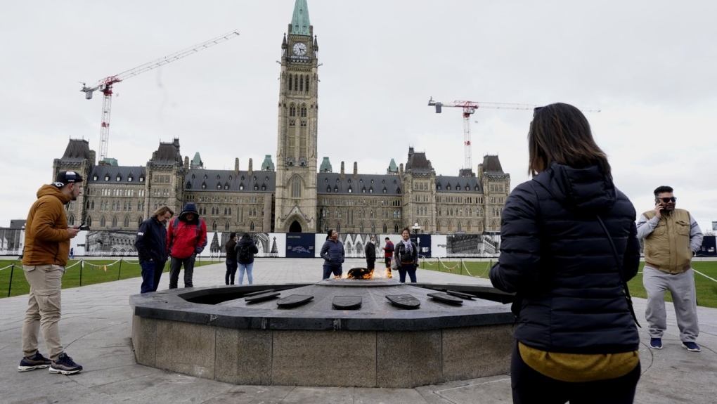 Visitors and tourists to Parliament Hill stand around the Centennial flame on Parliament Hill in Ottawa, Oct. 22, 2021. THE CANADIAN PRESS/Adrian Wyld