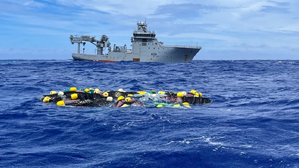 In this undated photo supplied by the New Zealand police, 
A shipment of cocaine floats on the surface of the Pacific Ocean with Royal New Zealand Navy vessel HMNZS Manawanui behind. (NZ Police via AP) 