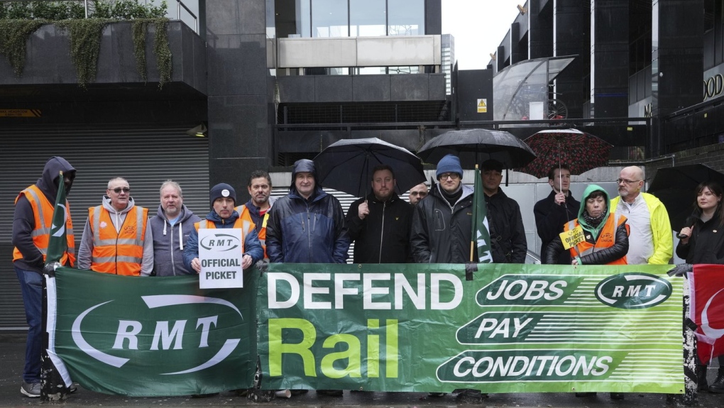 Mick Lynch, general secretary of the Rail, Maritime and Transport union (RMT), sixth left blue jacket, joins union members on the picket line during a rail strike in a long-running dispute over jobs and pensions, outside Euston station in London, Saturday March 18, 2023. (Jeff Moore/PA via AP)