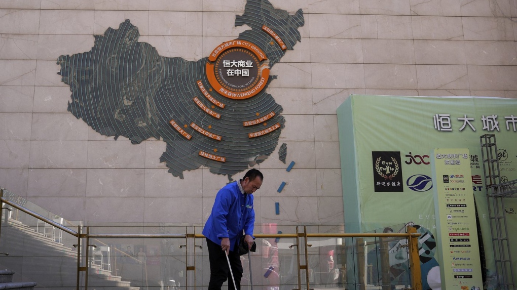 A cleaner sweeps near a map showing Evergrande development projects in China on a wall in an Evergrande city plaza in Beijing on Sept. 21, 2021. (AP Photo/Andy Wong, File)