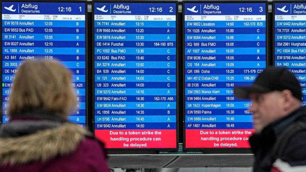 Passengers watch a screen showing cancelled flights at the airport in Duesseldorf during a national wide public transport strike, on March 27, 2023. (Martin Meissner / AP) 