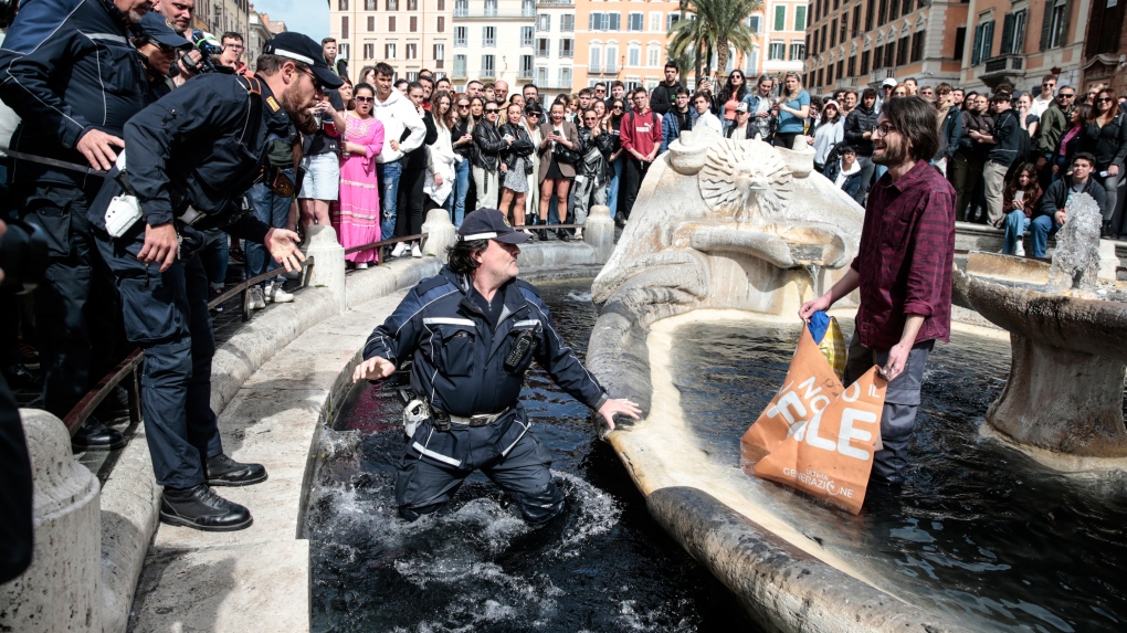 A police officer enters the fountain to remove an environmental activist. (Cecilia Fabiano/LaPresse/AP)

