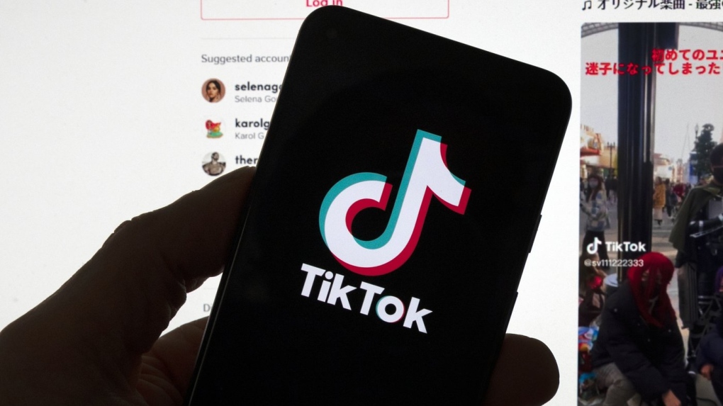 The TikTok logo is seen on a mobile phone in front of a computer screen which displays the TikTok home screen on Saturday, March 18, 2023, in Boston. A growing group of young Canadians rely on self teaching when it comes to personal finance, in the absence of financial literacy being taught in schools and households and with the rise in personal finance content being shared online, but experts caution that it's important to check the credentials of anyone offering advice. (AP-Michael Dwyer/THE CANADIAN PRESS)