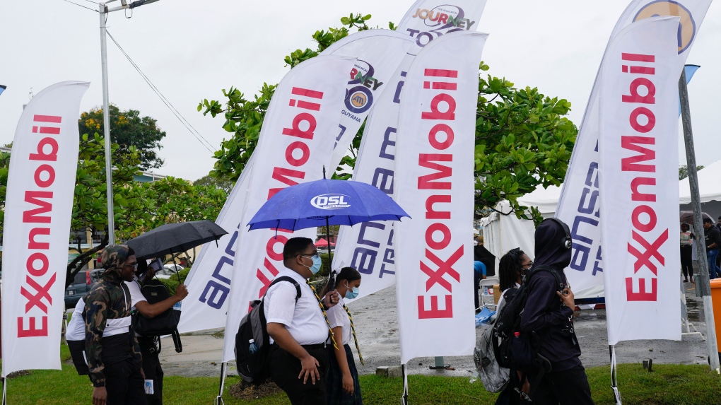 High school students walk past ExxonMobil flags as they arrive to a job fair at the University of Guyana in Georgetown, Guyana, Friday, April 21, 2023. (AP Photo/Matias Delacroix)