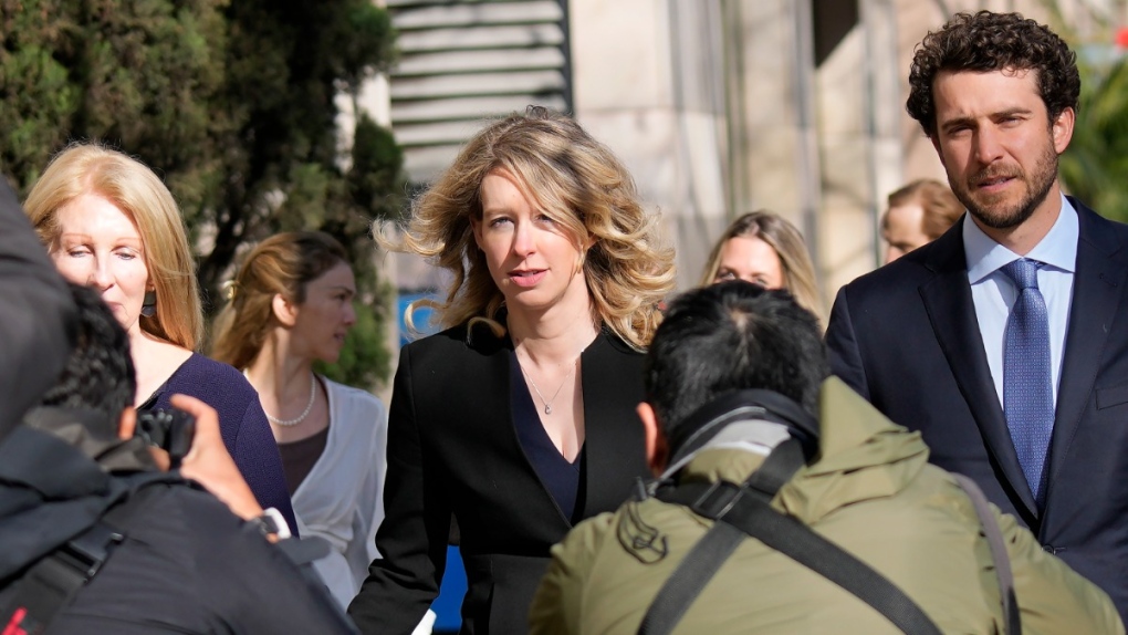 Former Theranos CEO Elizabeth Holmes, middle, walks to federal court with her partner, Billy Evans, right, and her mother, Noel Holmes, in San Jose, Calif., March 17, 2023. (AP Photo/Jeff Chiu)
