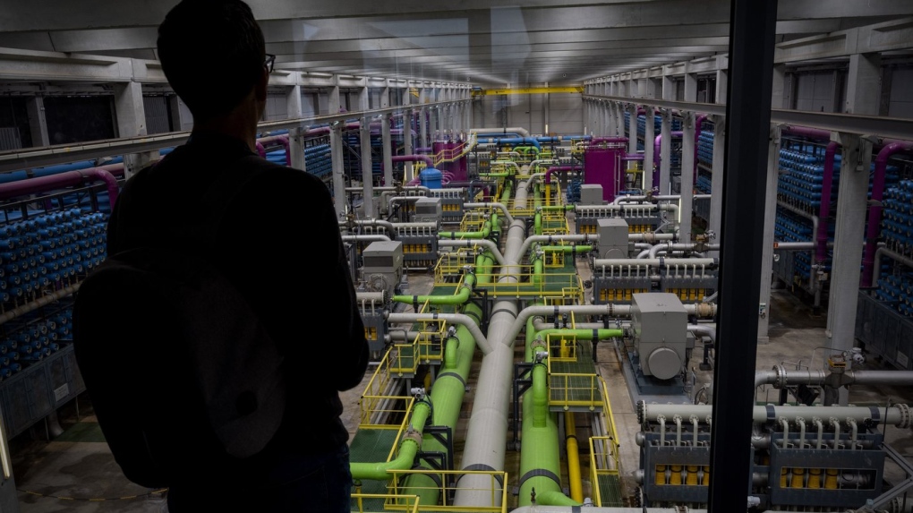 A person looks out at the view of the pipeline that transports seawater to filters at Europe's largest desalination plant for drinking water located in Barcelona, Spain, Tuesday, May 16, 2023. (AP Photo/Emilio Morenatti)