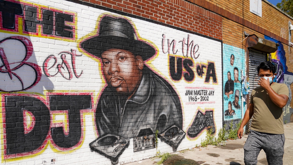 A pedestrian passes a mural of rap pioneer Jam Master Jay of Run-DMC, by artist Art1Airbrush, Aug. 18, 2020, in the Queens borough of New York. A third man has been charged in the 2002 shooting death of hip-hop trailblazer Jam Master Jay, prosecutors said Tuesday, May 30, 2023, adding another suspect in the Run-DMC member's killing which for years after it initially happened had languished as a cold case. (AP Photo/John Minchillo, File)