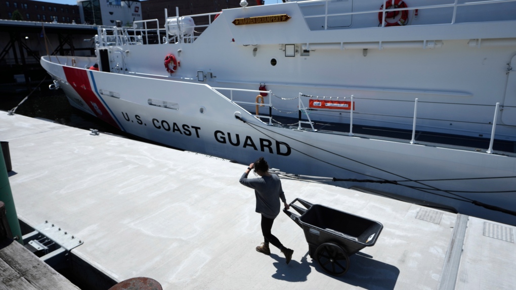 A person pulls a cart past the U.S. Coast Guard Cutter Warren Deyampert, docked at Coast Guard Base Boston, Thursday, June 22, 2023, in Boston. (AP Photo/Steven Senne)