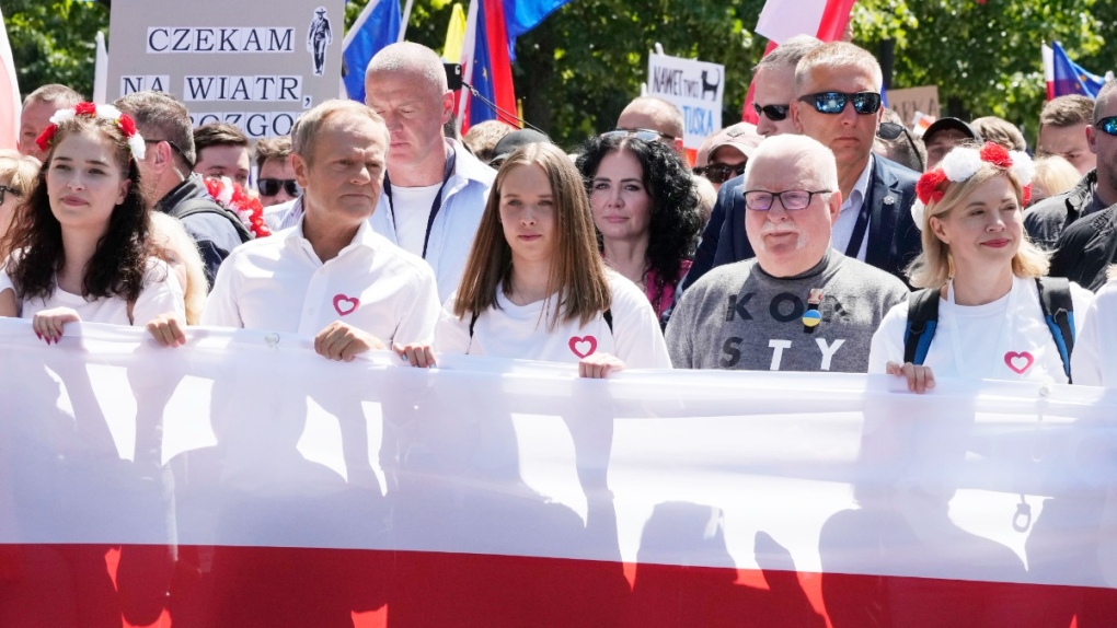 Participants join an anti-government march led by the centrist opposition party leader Donald Tusk, second left, and Lech Walesa, second right, who along with other critics accuse the government of eroding democracy, in Warsaw, Poland, June 4, 2023. (AP Photo/Czarek Sokolowski)