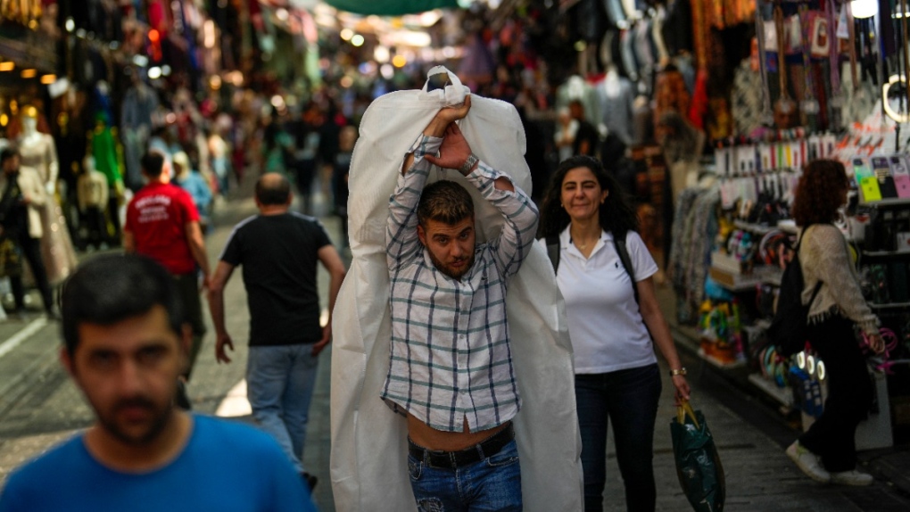 A man carries goods in a street market at Eminonu commercial area in Istanbul, Turkiye, June 7, 2023. (AP Photo/Francisco Seco)