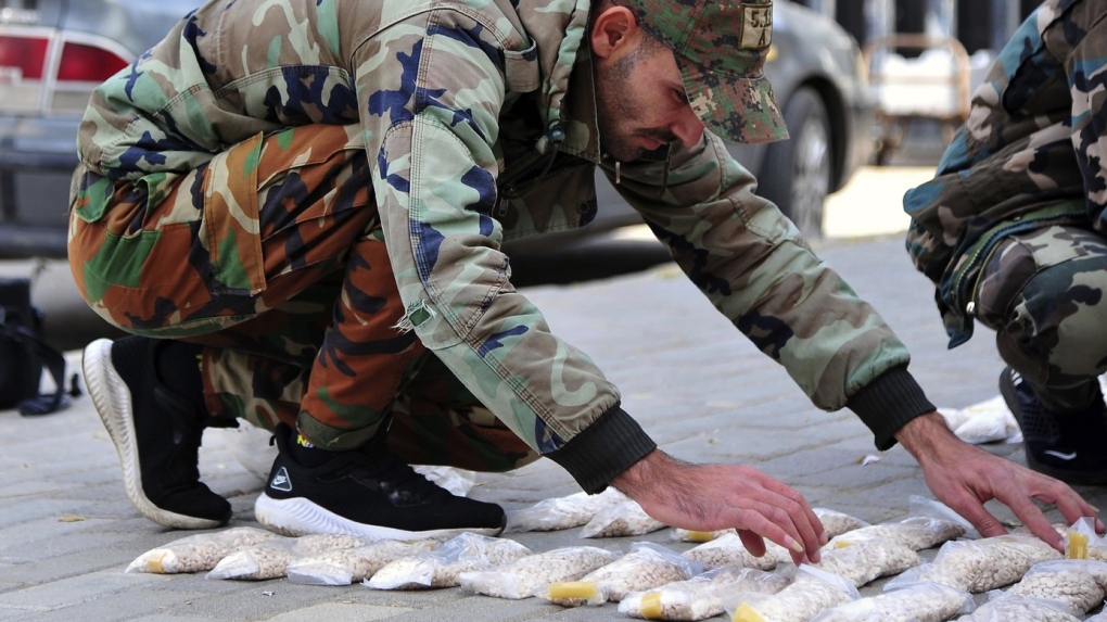  In this photo released by the Syrian official news agency SANA, a Syrian soldier displays Captagon pills, in rural Damascus, Syria, Tuesday, Nov. 30, 2021. (SANA via AP, File)