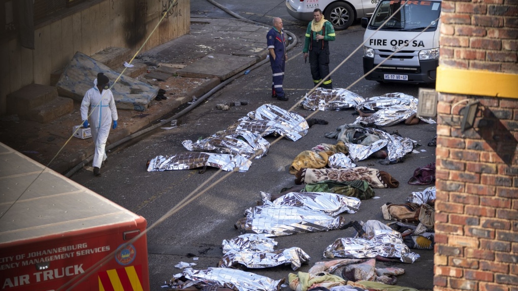 Medics stand by the covered bodies of victims of a deadly blaze in downtown Johannesburg, Aug. 31, 2023. (AP Photo/Jerome Delay)