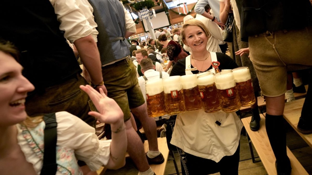 A waitress carries glasses of beer on day one of the 188th 'Oktoberfest' beer festival in Munich, Germany, Saturday, Sept. 16, 2023. (AP Photo/Matthias Schrader)