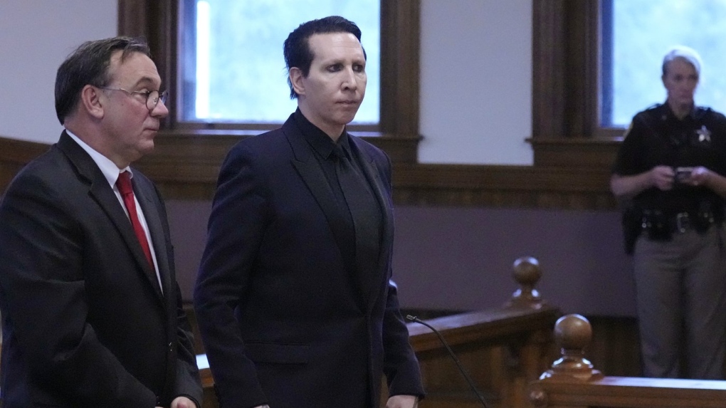 Musical artist Marilyn Manson, whose legal name is Brian Hugh Warner, centre, stands with his attorney Kent Barker during an appearance in Belknap Superior Court, Sept. 18, 2023, in Laconia, N.H. Manson, who was charged with charged with two misdemeanor counts of simple assault, was accused of approaching a videographer at his 2019 concert in New Hampshire and allegedly spitting and blowing his nose on her. (AP Photo/Charles Krupa)