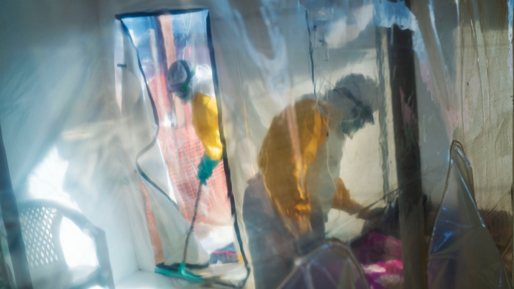 In this July 13, 2019, file photo, health workers wearing protective suits tend to an Ebola victim kept in an isolation cube in Beni, Congo. (AP Photo/Jerome Delay, File)
