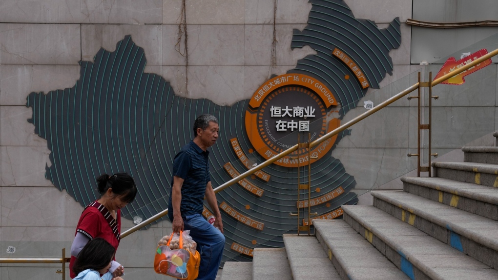 Residents walk past a map showing Evergrande development projects in China, at an Evergrande city plaza in Beijing, Sept. 18, 2023. (AP Photo/Andy Wong)