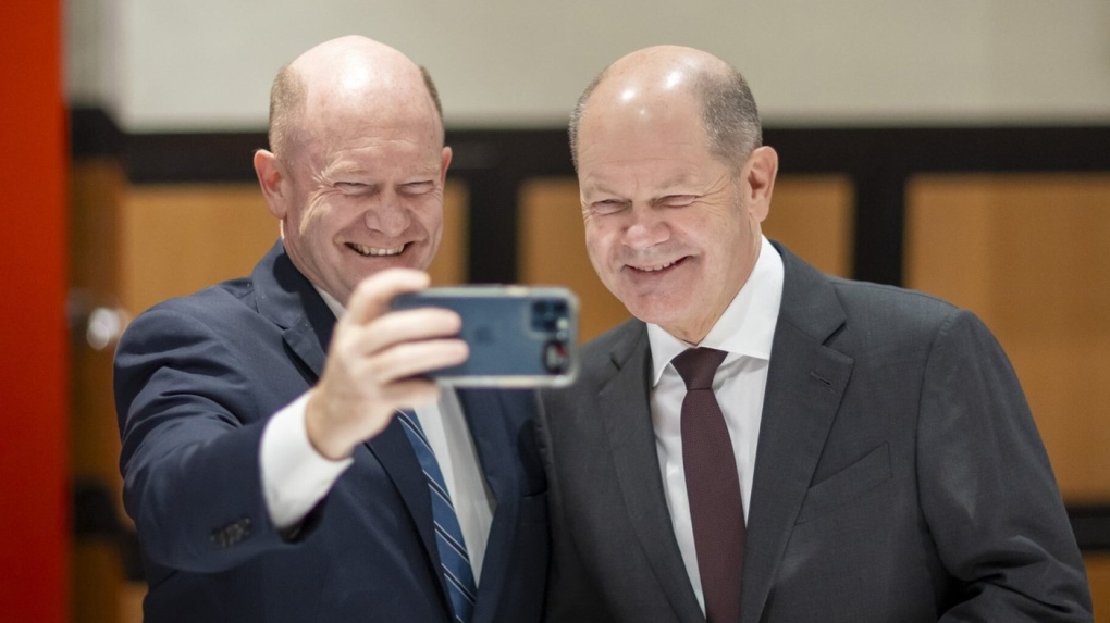 In this photo provided by Bundesregierung, from left, U.S. Sen. Chris Coons, D-Del., and German Chancellor Olaf Scholz pose for a selfie on X, formerly Twitter. Both were seeing double when they met in Washington, D.C., this week and went on social media to share their mirror image with the world. (Bundesregierung via AP)