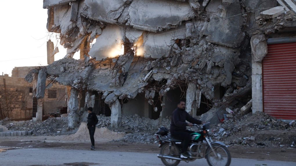 People pass by the house destroyed in the February 2023 earthquake in Jinderis, Syria, on Jan. 27, 2024. (AP Photo/Omar Albam)