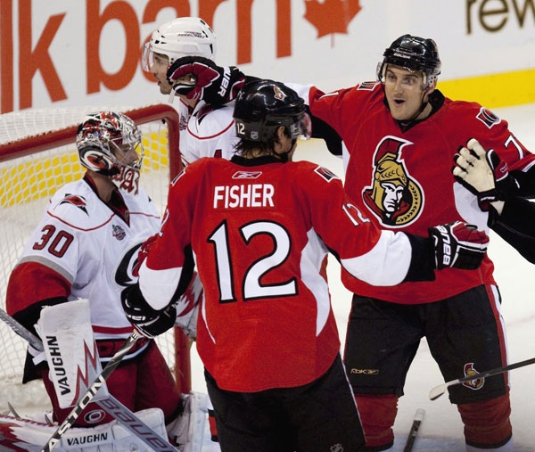 Ottawa Senators' Mike Fisher, middle, celebrates his first goal of the season with teammate Nick Foligno, right, against the Carolina Hurricanes' Cam Ward, left, during first period NHL hockey action at the Scotiabank Place in Ottawa on Thursday, Oct. 14, 2010. THE CANADIAN PRESS/Sean Kilpatrick