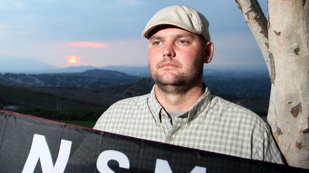 In this file photo taken Friday, Oct. 22, 2010, Jeff Hall holds a neo-Nazi flag while standing near his home in Riverside, Calif. (AP Photo/Sandy Huffaker, File)