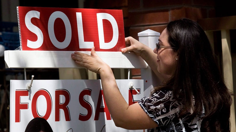 A real estate agent puts up a 'sold' sign in front of a house in Toronto on Tuesday, April 20, 2010. (Darren Calabrese / THE CANADIAN PRESS)