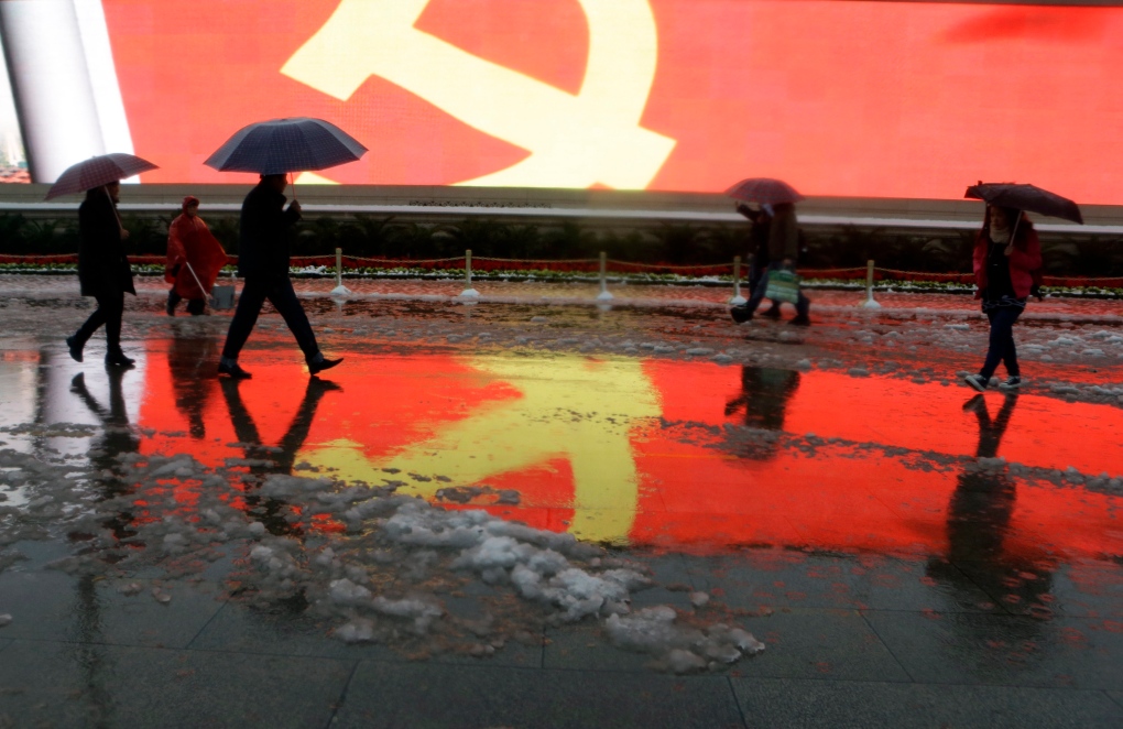Residents walk past China Communist Party flag
