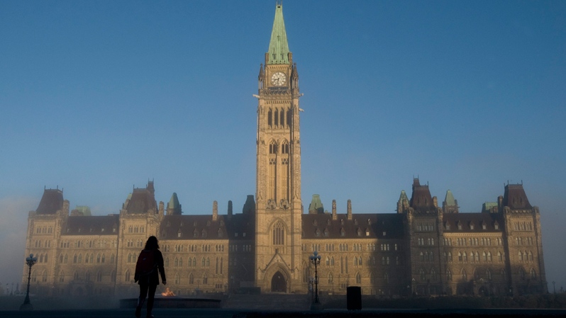 Sun illuminates the Peace Tower as a visitor makes their way onto Parliament Hill in Ottawa, Wednesday, Nov. 3, 2010. (Adrian Wyld / THE CANADIAN PRESS)  