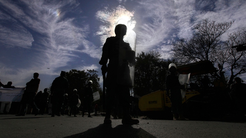 An Afghan police officer is silhouetted as he stands guard during a protest against the September parliamentary poll in Kabul, Afghanistan, Wednesday, Nov. 3, 2010. (AP / Altaf Qadri)