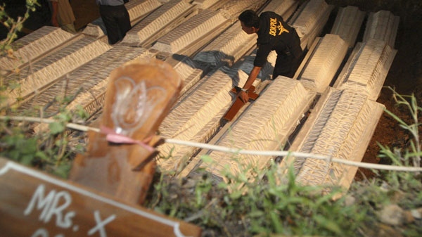 An Indonesian police walks in middle of coffins at the grave for mass burial of the victims of Mount Merapi eruption at Sleman, Yogyakarta, Indonesia, Sunday, Nov. 7, 2010. (AP / Achmad Ibrahim)