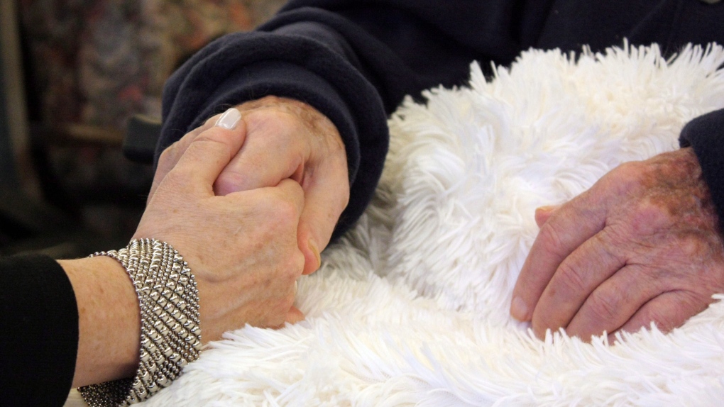 Woman holds her father's hand at Sunnybrook centre