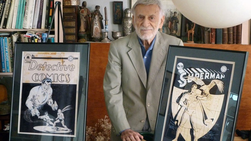 In this undated photo released Monday, Nov. 8, 2010 by ComicConnect.com, Jerry Robinson, who created the Joker, stands with the two framed covers, Superman #14 and Detective Comics #69, that will be offered for auction on ComicConnect.com. (AP Photo/ComicConnect.com)