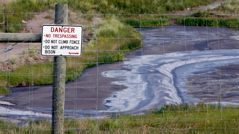 Tailings drain into a pond at the Syncrude oilsands mine facility near Fort McMurray, Alta. on July 9, 2008. (Jeff McIntosh / THE CANADIAN PRESS)