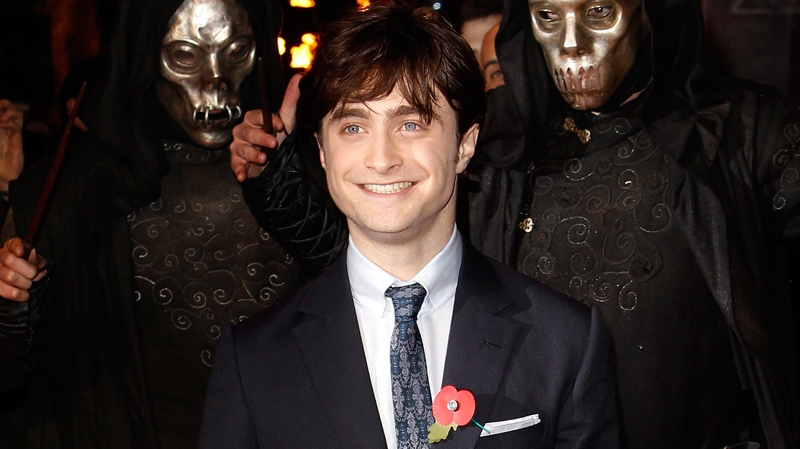 Daniel Radcliffe arrives at a cinema in London's Leicester Square for the world premiere of 'Harry Potter and the Deathly Hallows: Part 1,' as masked actors stand behind, Thursday, Nov. 11, 2010. (AP / Joel Ryan)