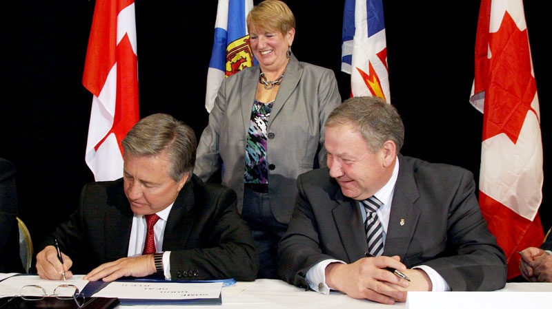 Newfoundland and Labrador Premier Danny Williams (left) signs the agreement to develop the Lower Churchill hydroelectric project in Labrador with help from Nova Scotia as Nova Scotia Premier Darrell Dexter, while Newfoundland and Labrador Natural Resources Minister Kathy Dunderdale look on at a news conference in St. John's, Thursday, Nov.18, 2010. (Rhonda Hayward / THE CANADIAN PRESS)