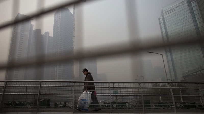 A man walks on a pedestrian overpass on a hazy day at Beijing's Central Business District, China, Friday, Nov. 19, 2010. (AP Photo/Alexander F. Yuan)