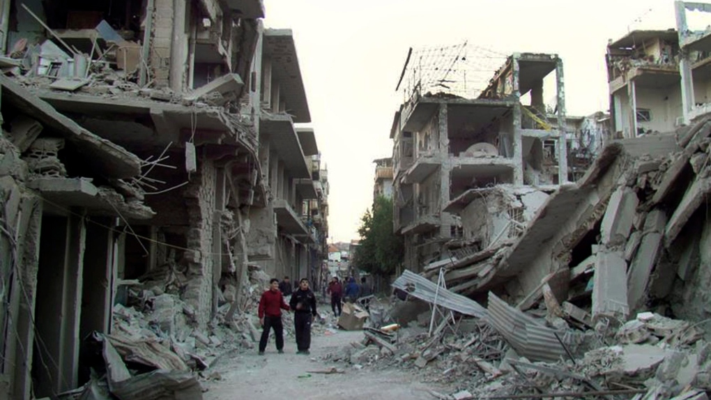 Syrian citizens walk in a destroyed street