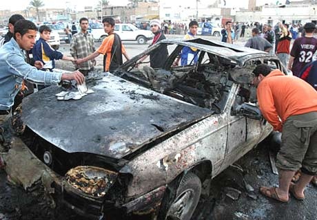 Iraqis gather to inspect the damage to a car destroyed in a car bomb blast in Baghdad's Shiite enclave of Sadr City, Iraq,  Feb. 21, 2007.  (AP / Karim Kadim)