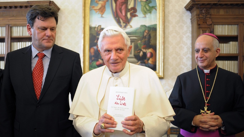 In this picture made available by the Vatican newspaper Osservatore Romano Pope Benedict XVI, flanked by German journalist Peter Seewald, left, and by Monsignor Rino Fisichella holds a copy of the book 'Light of the World' during a private audience at the Vatican, Tuesday, Nov. 23, 2010.