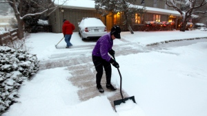 A woman and her husband shovel their walk